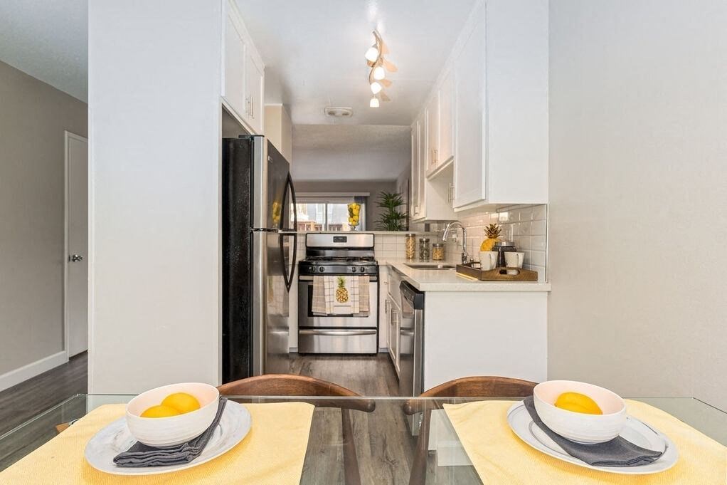 A modern kitchen with a black refrigerator and a breakfast table set with two bowls of fruit at Nola 624 Apartments, California