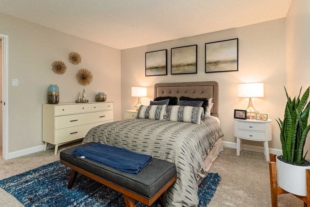 A bedroom with a bed, nightstands, and a rug at Nola 624 Apartments, California