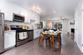 A kitchen with a table set for two with a pineapple towel on the oven door.