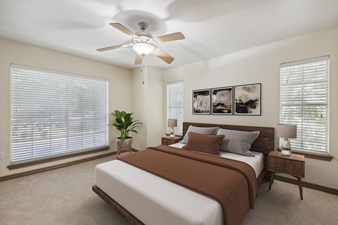A bedroom with a bed, a ceiling fan, and a potted plant.