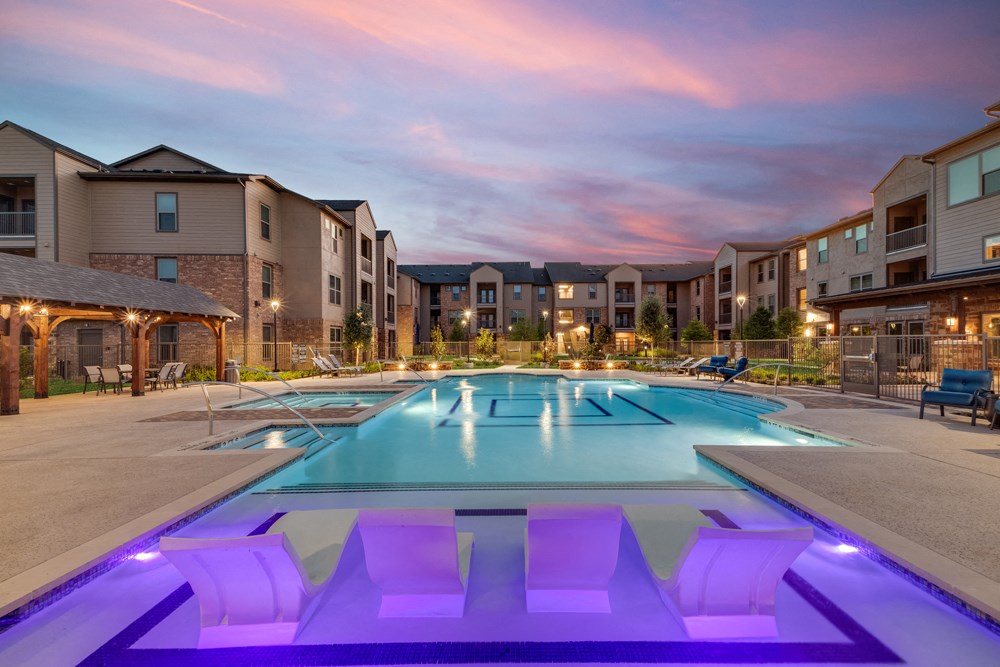 apartments with a pool with purple lights at dusk