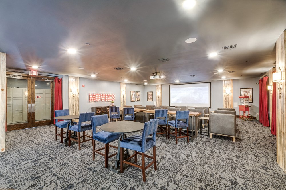 Prosper, TX Pet-Friendly Apartments - Alders Prosper - Conference Room With Tables, Chairs, Popcorn Machine, And Projector Screen