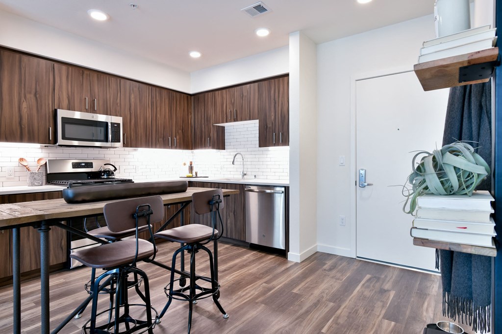 a kitchen with a bar and stools in front of a counter with three chairs