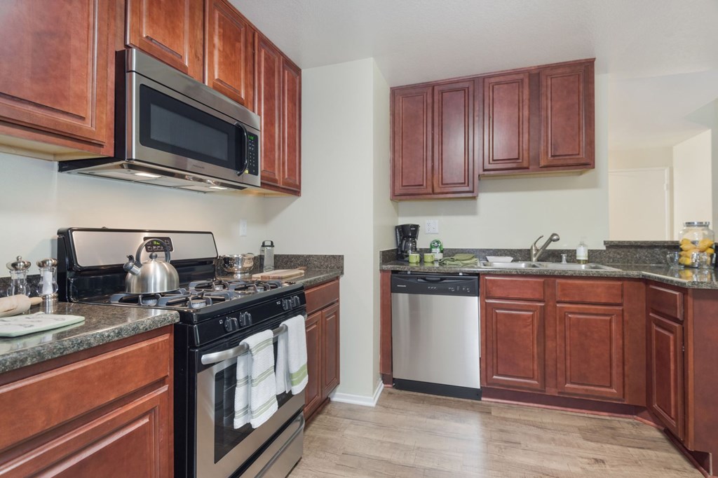 A kitchen with dark wood cabinets and a black stove top.at Norwalk Metropointe, California  