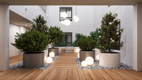 A modern outdoor space with wooden floors, potted trees, and hanging lights.