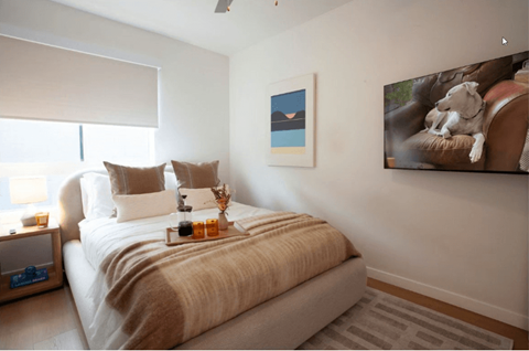 A bedroom with a bed, a nightstand, and a painting on the wall.