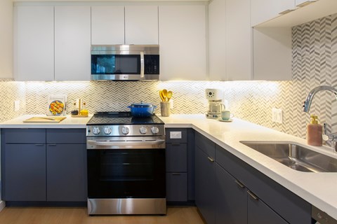 A modern kitchen with a stove top oven and a microwave above it.