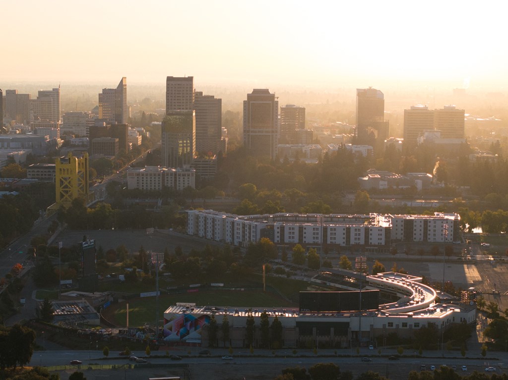 an aerial view of a city at sunset with highways and skyscrapers