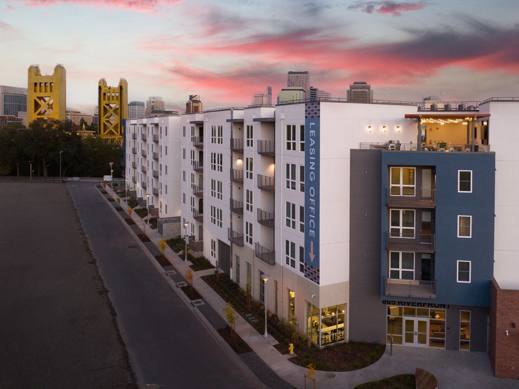 an aerial view of an apartment building with a sunset in the background
