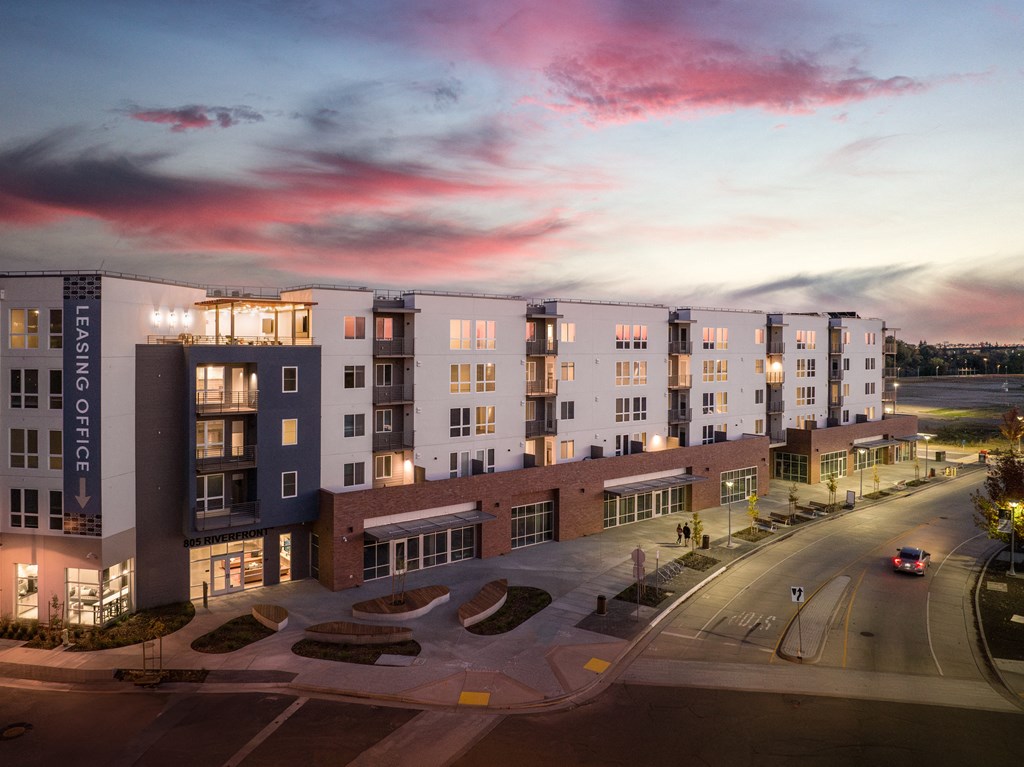 an aerial view of an apartment building on a city street at sunset