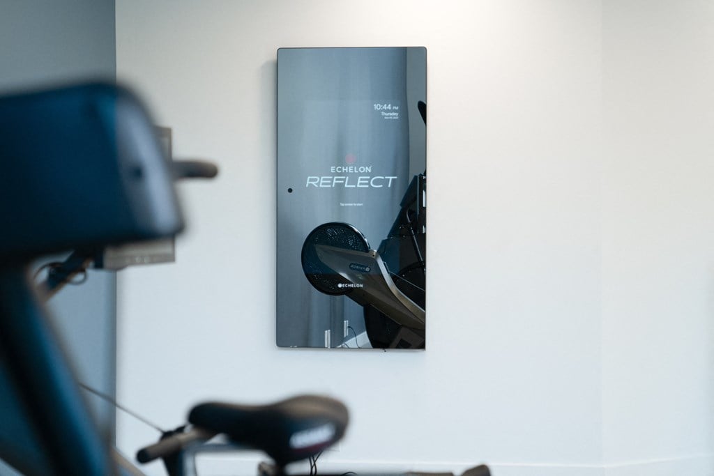 a poster hanging on the wall of a gym room with a bike and a mirror