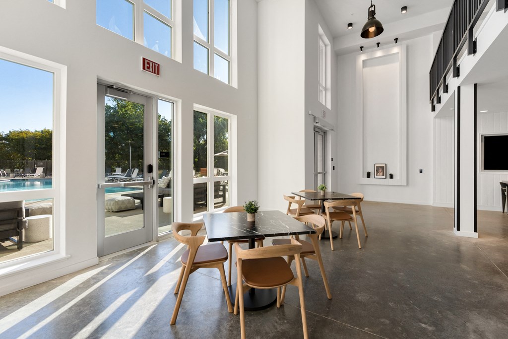a dining area with a table and chairs and large windows