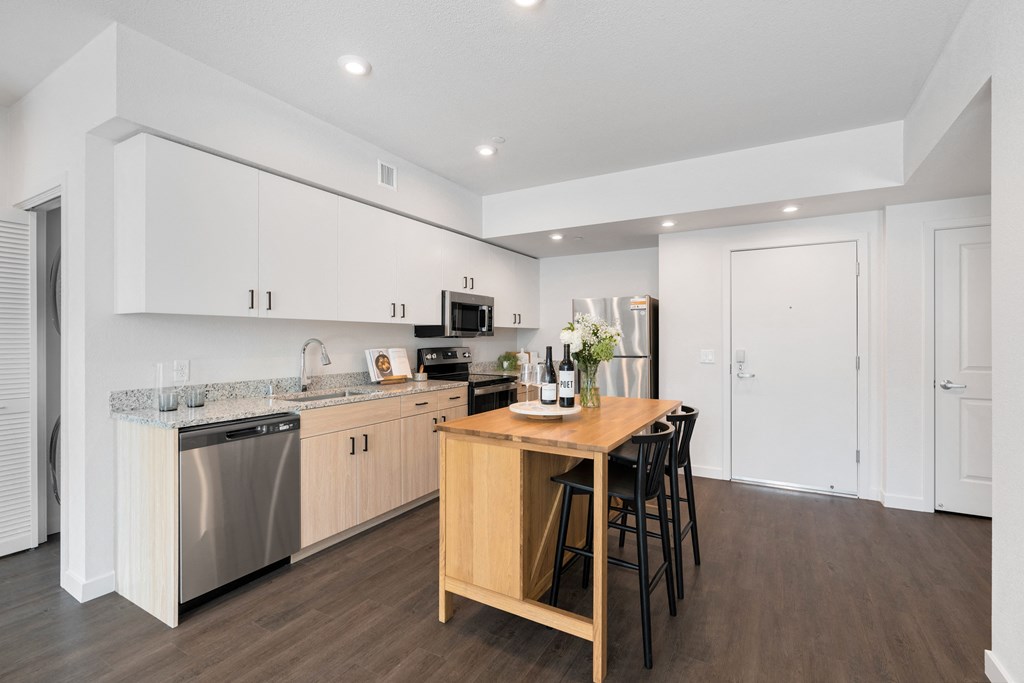 a kitchen with white cabinets and a wooden island with chairs