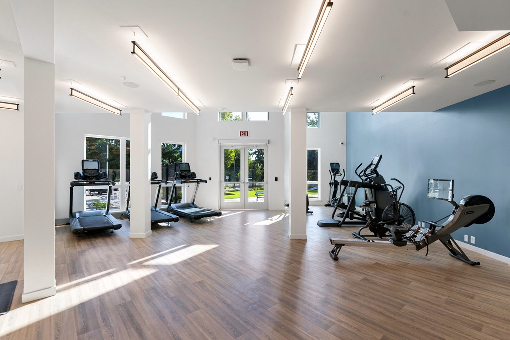 a gym with cardio machines and weights on a wooden floor