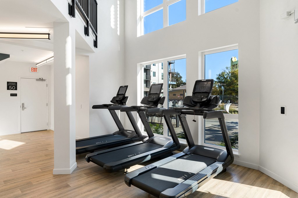 three treadmills in a room with windows and a door
