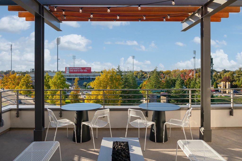 a balcony with tables and chairs and a view of a baseball field