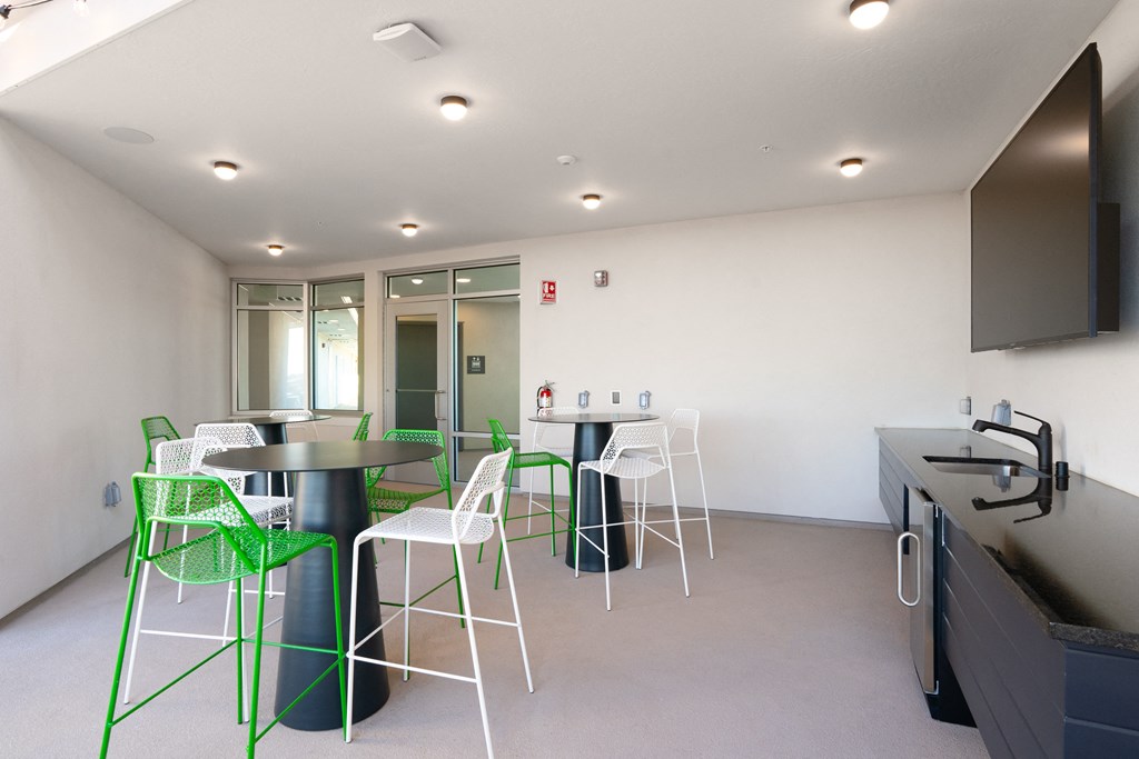 a room with tables and chairs and a kitchen