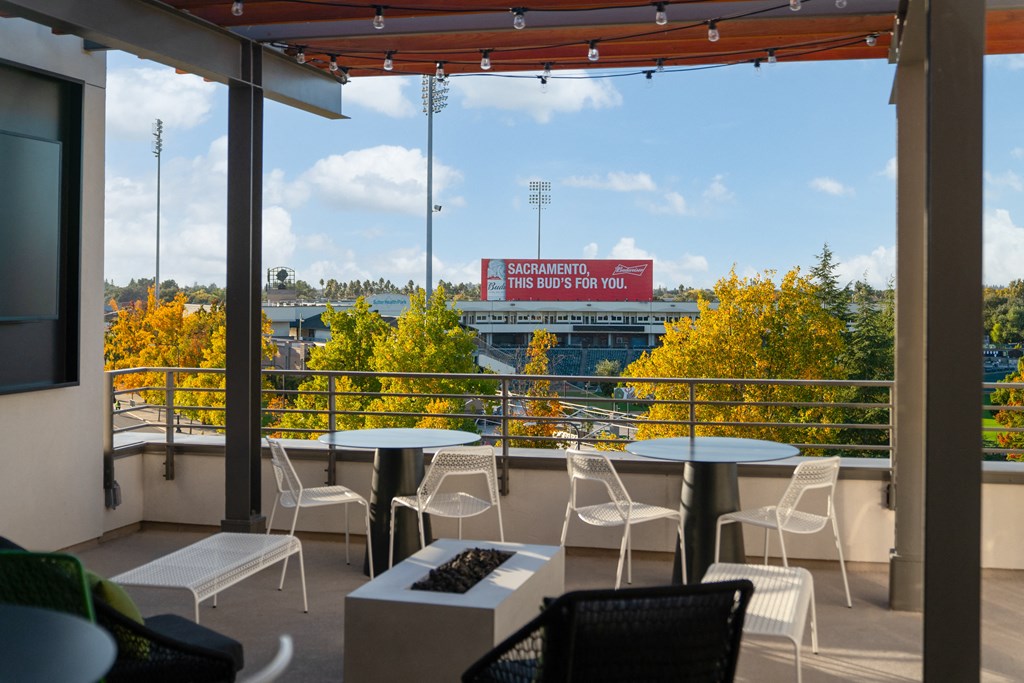 a balcony with tables and chairs and a view of a baseball field