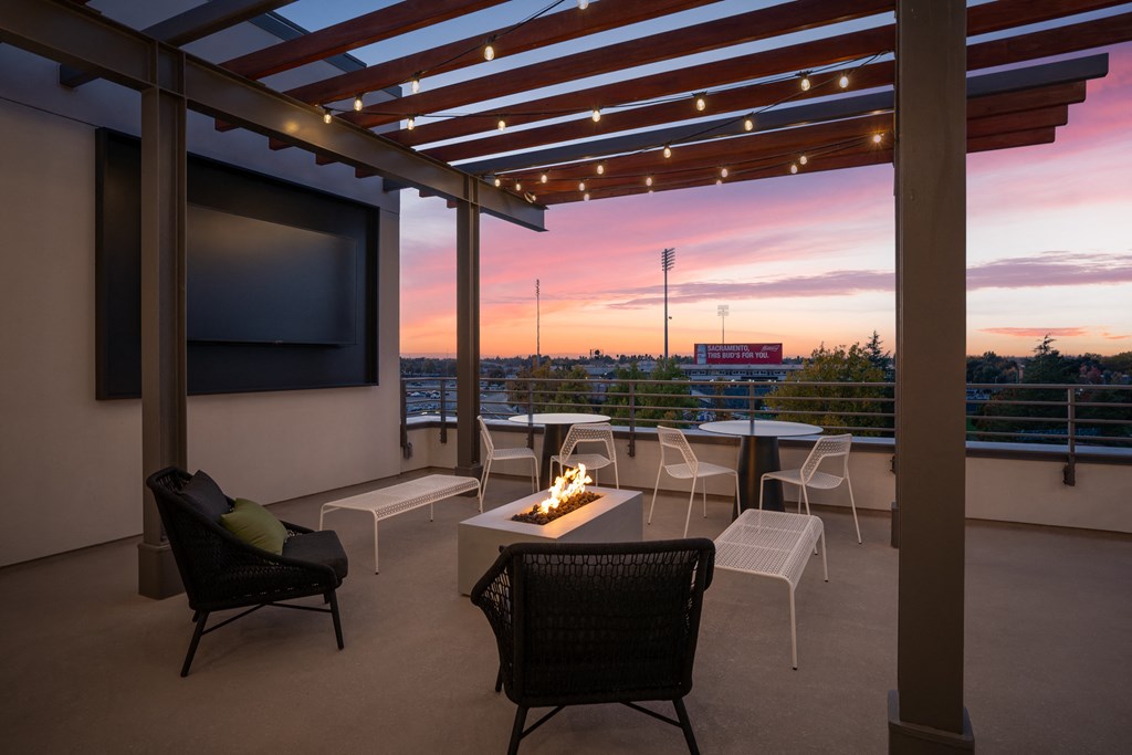 a terrace with chairs and a fire pit and a tv on a
