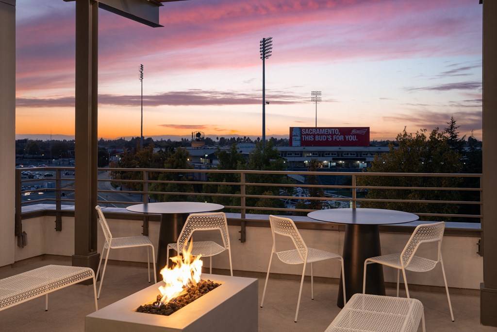 a patio with tables and chairs and a fire pit and a view of the city