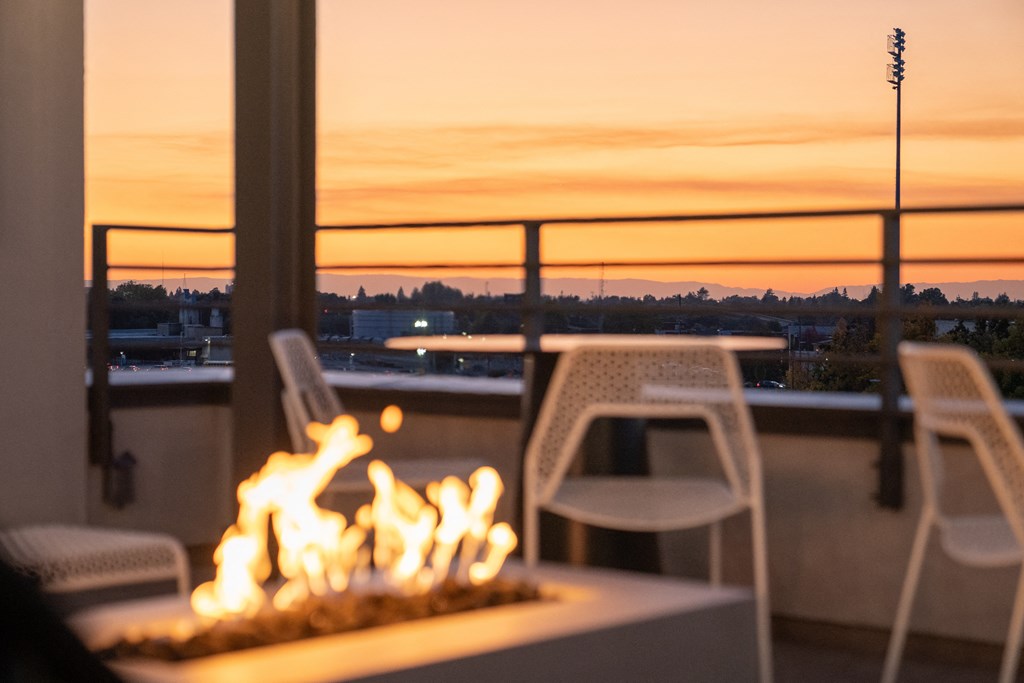 a table with a fire on a balcony with a view of the sunset