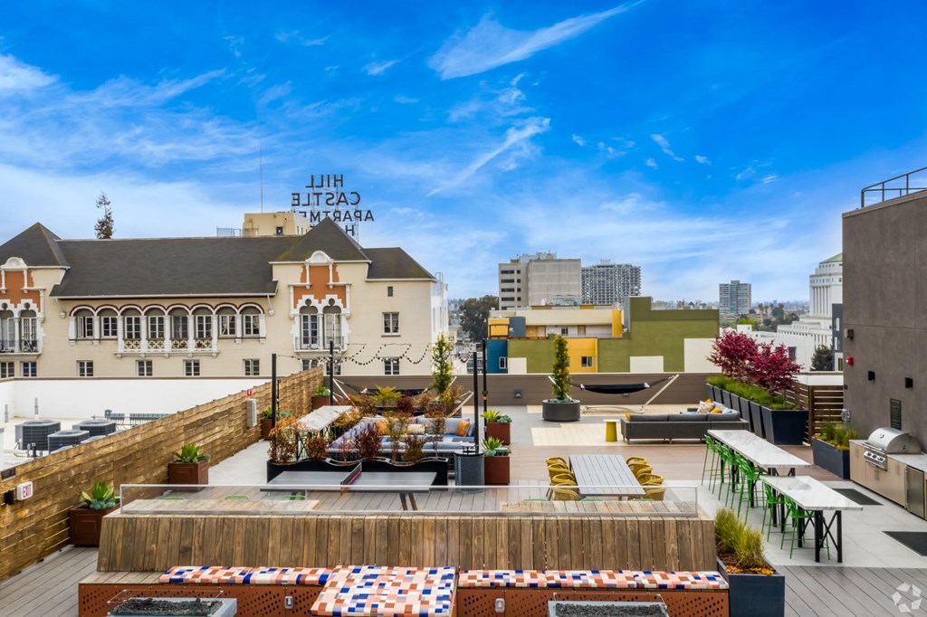 a rooftop terrace with tables and chairs and a city in the background