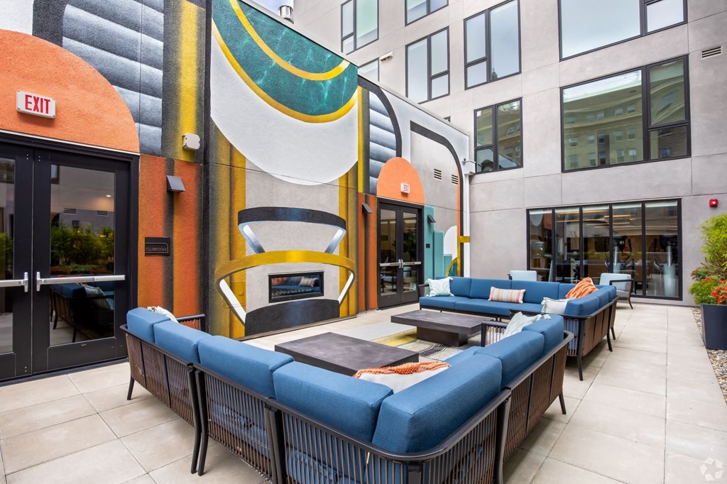 a patio with couches and tables in front of a building