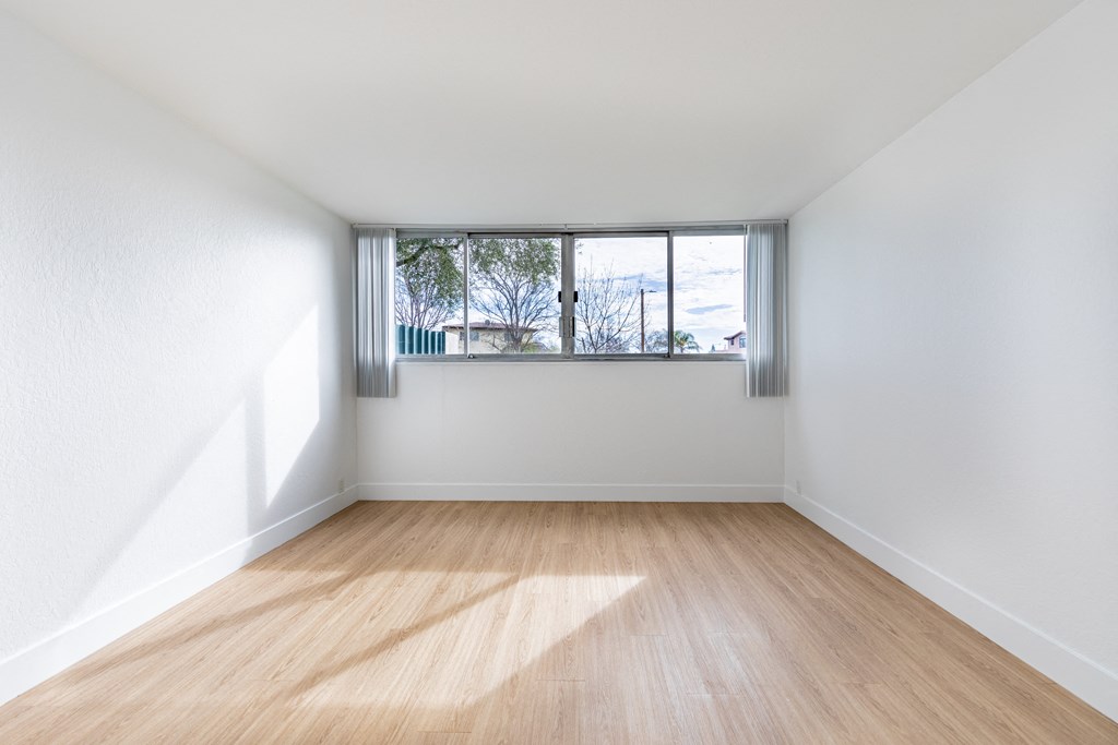 an empty room with wooden floors and a window at Avenue Two Apartments, Redwood City  , CA