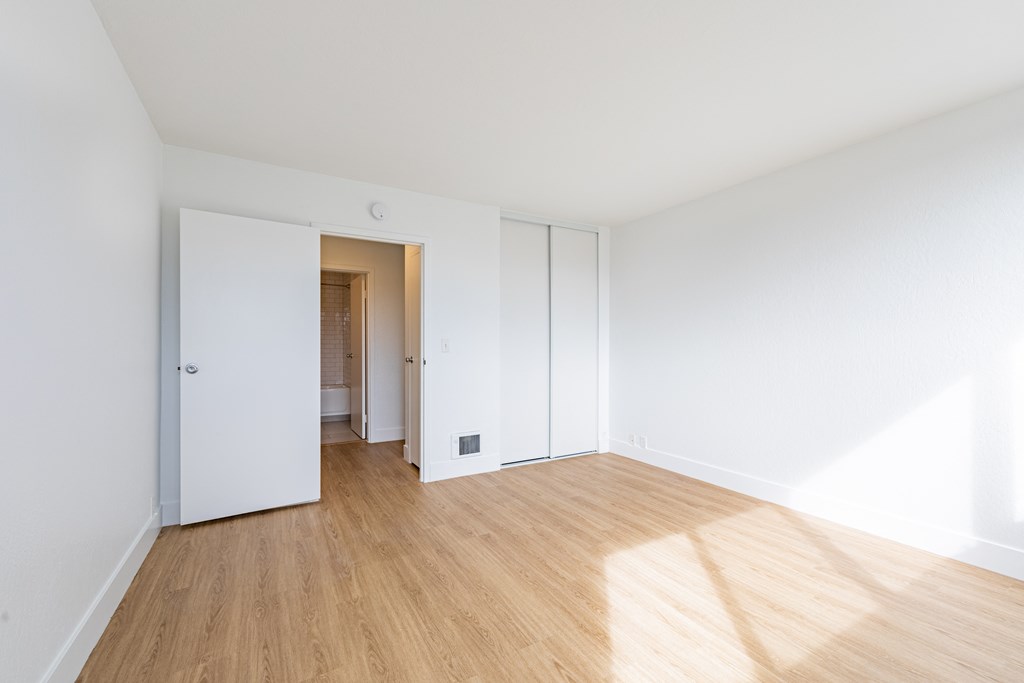a living room with white walls and a wooden floor at Avenue Two Apartments, Redwood City  ,California, 94063