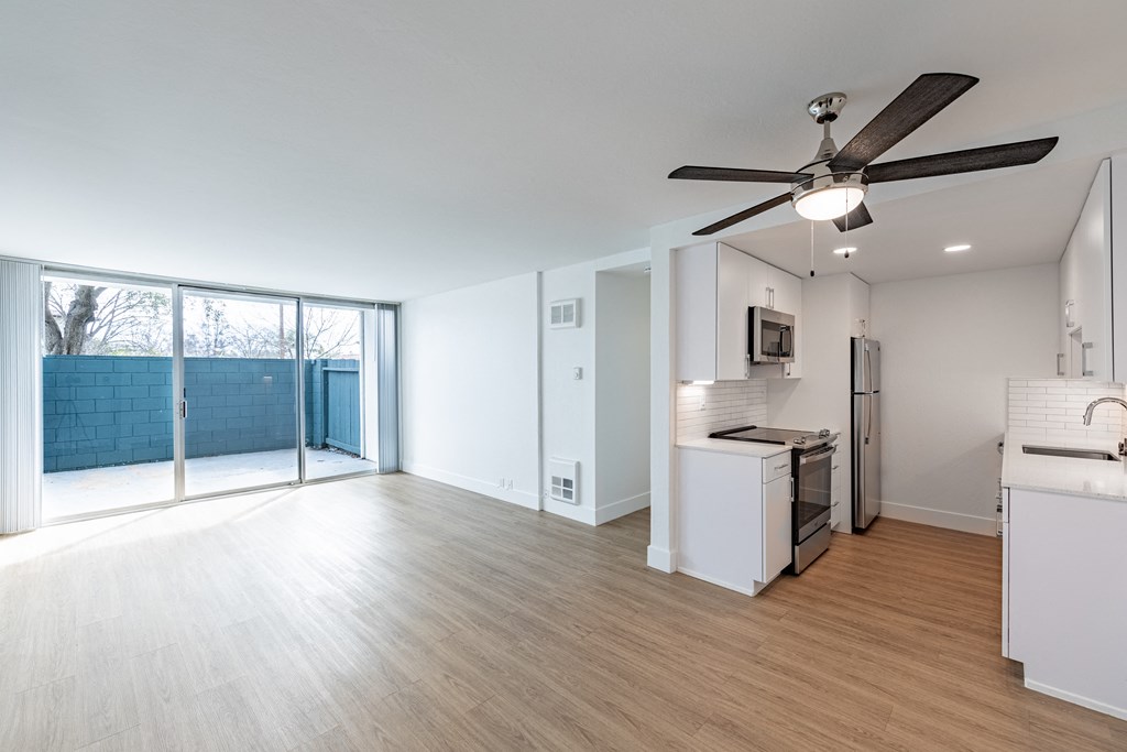 an empty living room and kitchen with a sliding glass door to a patio at Avenue Two Apartments, California