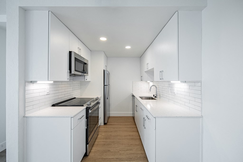 a kitchen with white cabinets and a stove and a refrigerator at Avenue Two Apartments, California