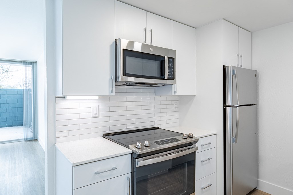 a kitchen with white cabinets and stainless steel appliances and a refrigerator at Avenue Two Apartments, California, 94063