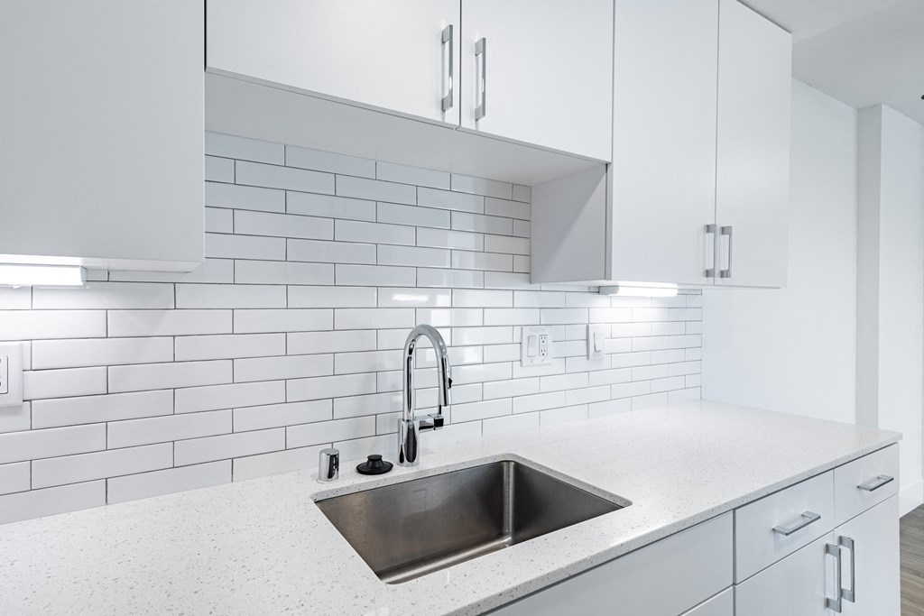 a white kitchen with a sink and white tiles at Avenue Two Apartments, Redwood City  , California