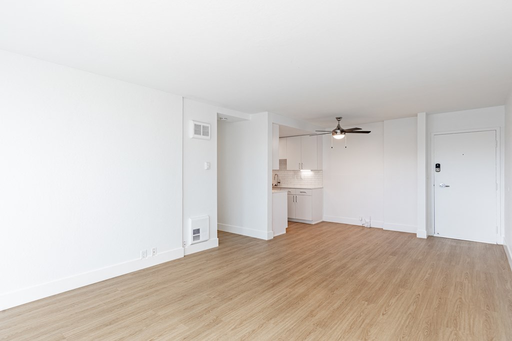 an empty living room and kitchen with white walls and wood flooring at Avenue Two Apartments, Redwood City