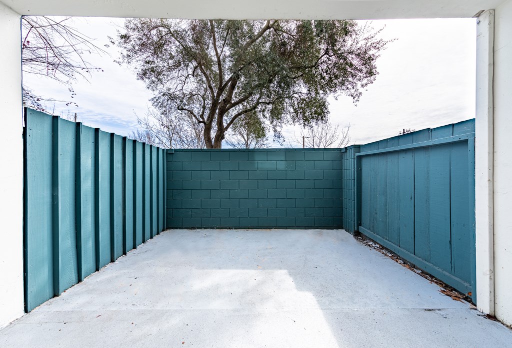 a garage with a blue fence and a tree behind it at Avenue Two Apartments, Redwood City  , CA 94063