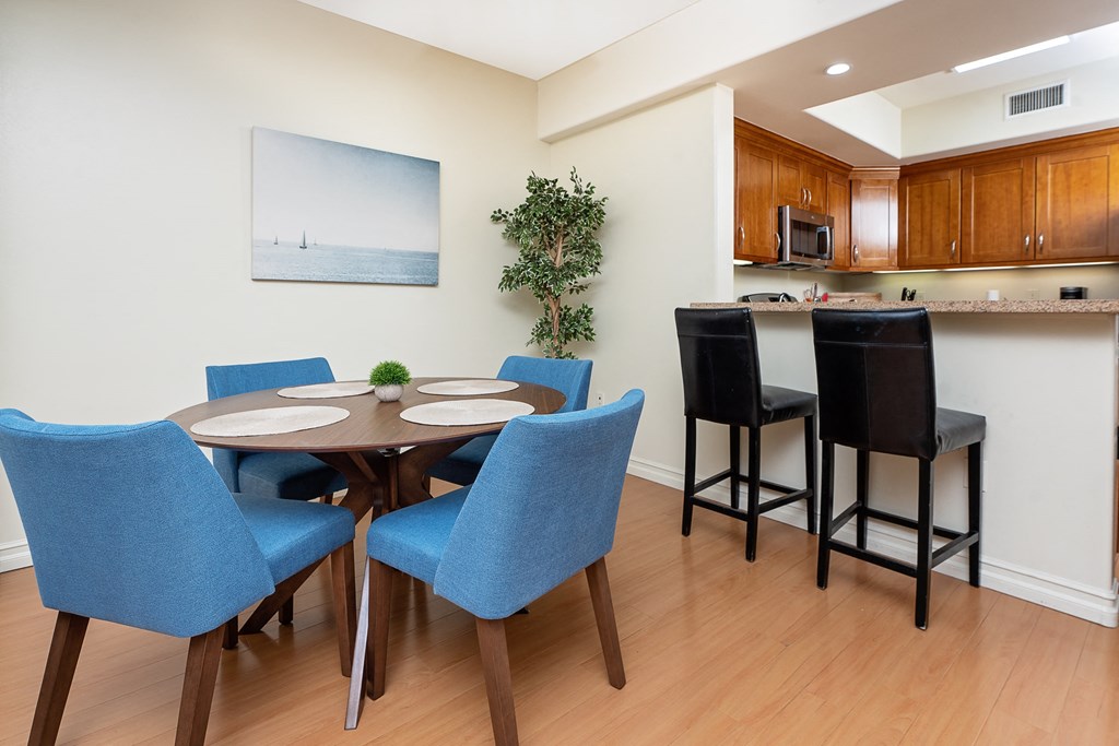 a dining area with a table and chairs and a kitchen in the background