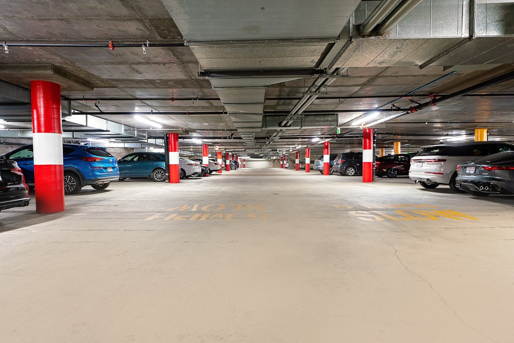a parking garage with cars and red and white pillars