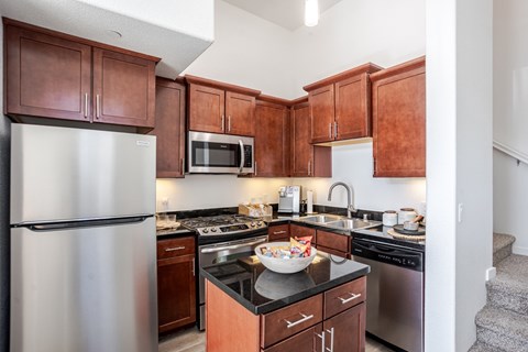 A kitchen with brown cabinets and a stainless steel refrigerator.