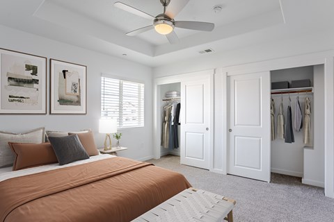 A bedroom with a bed, a ceiling fan, and a closet.