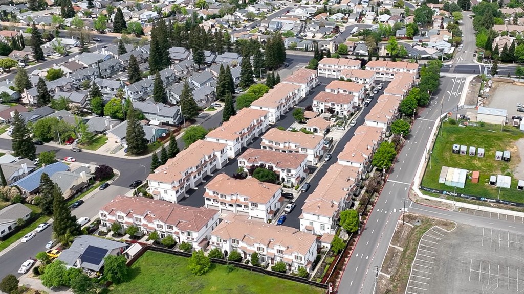 A large apartment complex is surrounded by smaller buildings and trees.