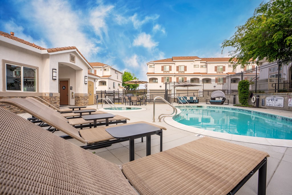 A pool area with sun loungers and a building in the background.
