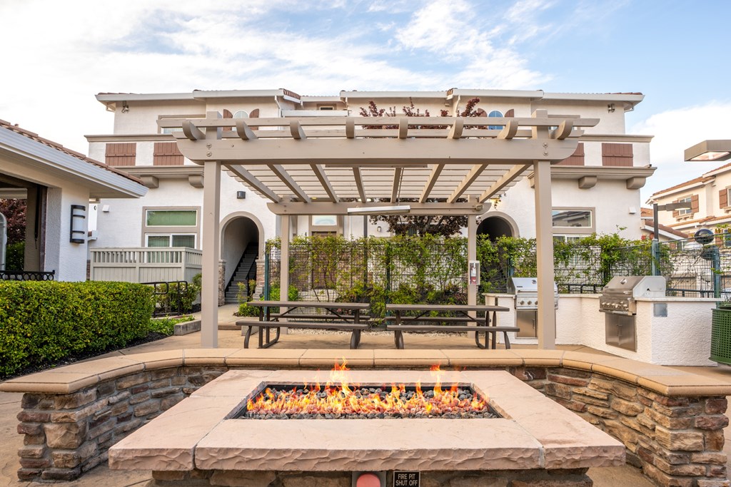 A patio with a fire pit and picnic tables.