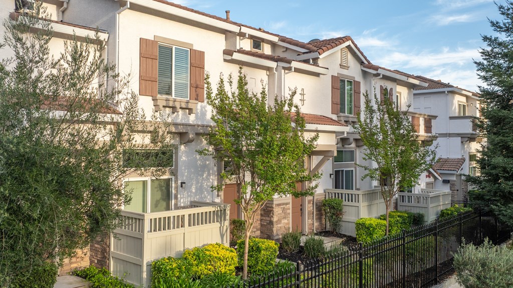 A row of houses with a black fence in front.