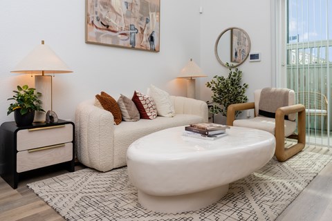 A living room with a white sofa, a white coffee table, and a black side table with a lamp.
