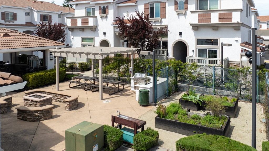 A courtyard with a bench, a table, and a fence.