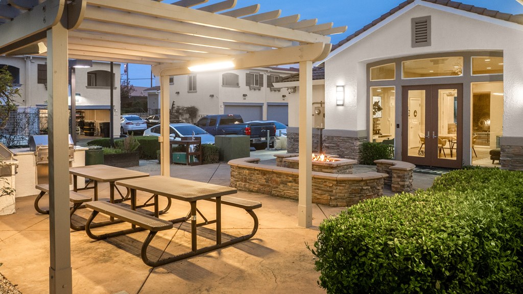 A patio with a picnic table and a fire pit.