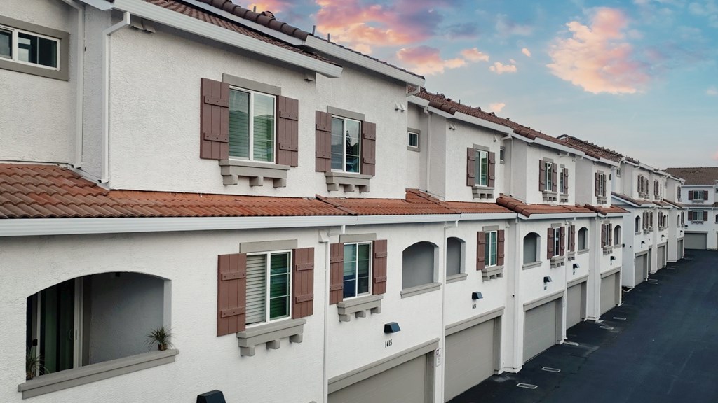 A row of white houses with red roofs and brown shutters.