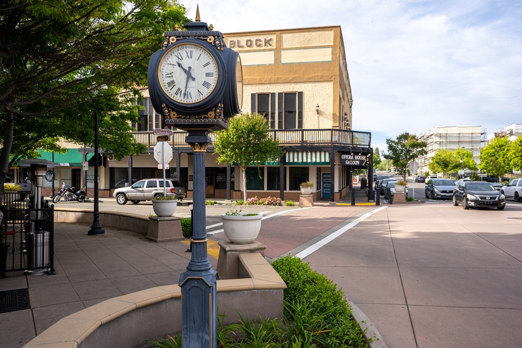 A street view with a clock on a pole in the foreground.