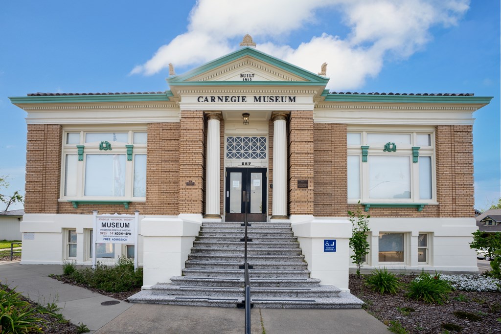 The Carnegie Museum is a two-story building with a green roof and a sign on the front.