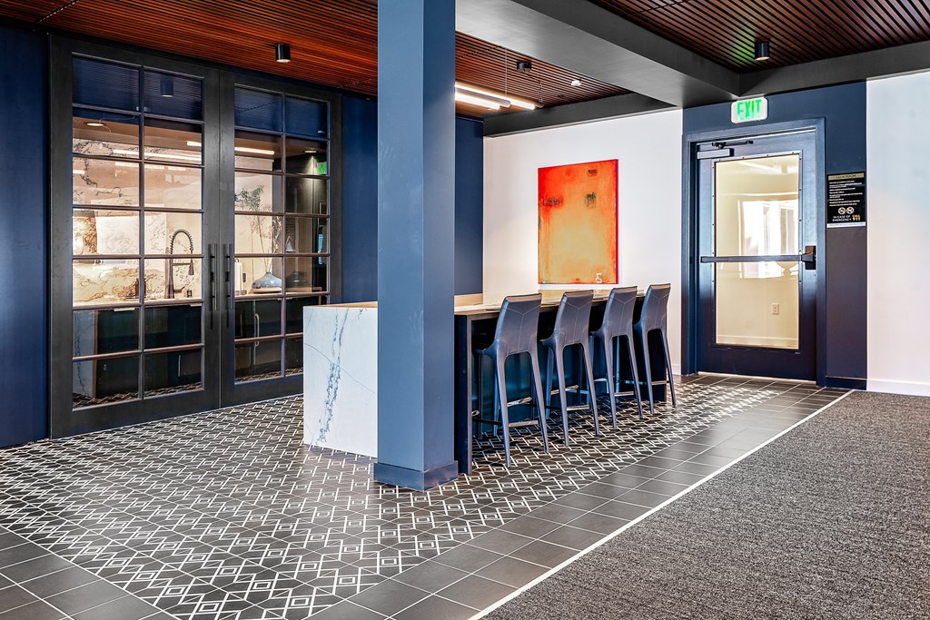 a table and chairs in front of a door with a red painting on the wall